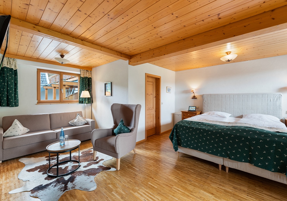 Hotelzimmer im Landhausstil mit Doppelbett und gemütlicher Couch-Ecke